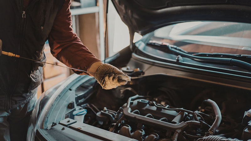 Mechanic working on a modern car engine in an automotive workshop.