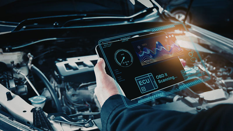 Technician diagnosing a modern car engine using advanced digital diagnostic tools.