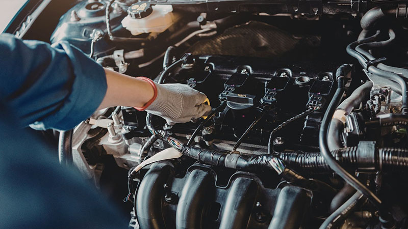 Mechanic inspecting car engine components during diagnostic check for low engine compression.