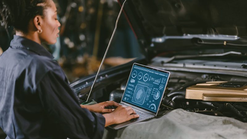 Mechanic working on a laptop to diagnose or program Engine Control Units (ECUs) in a vehicle