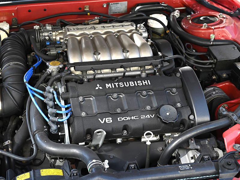 Close-up of a Mitsubishi engine under the hood showing the engine bay and components.