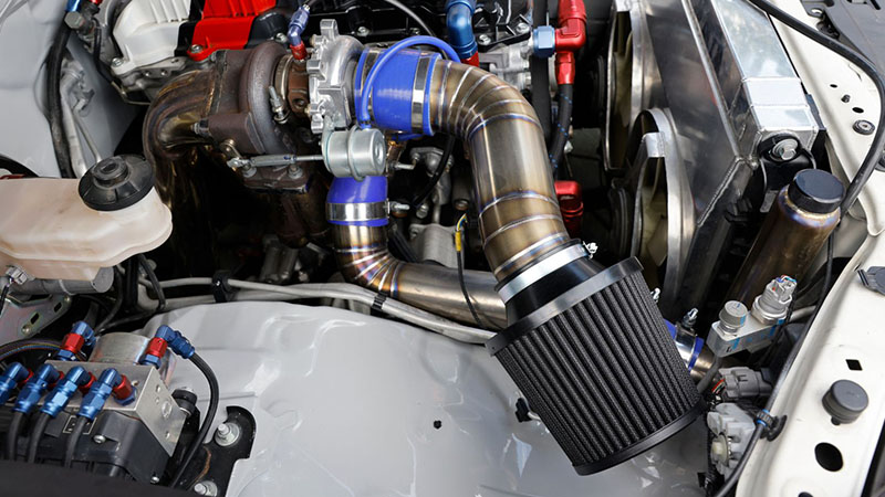 Close-up of a turbocharger and wastegate assembly on a race car engine.