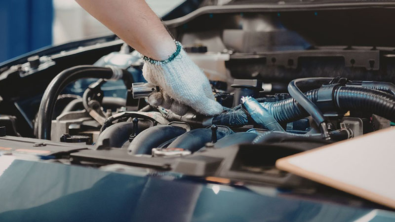 Auto mechanic working on engine repair inside vehicle engine bay.
