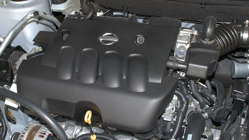 Nissan MR20DE engine under hood close-up with visible components.