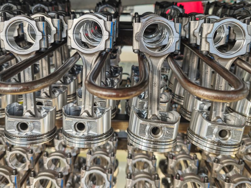 Close-up view of multiple rows of engine pistons, showcasing precision engineering and metallic finish.