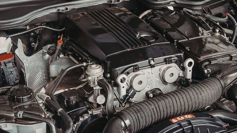 Detailed view of a car engine bay showing engine components and surrounding parts.
