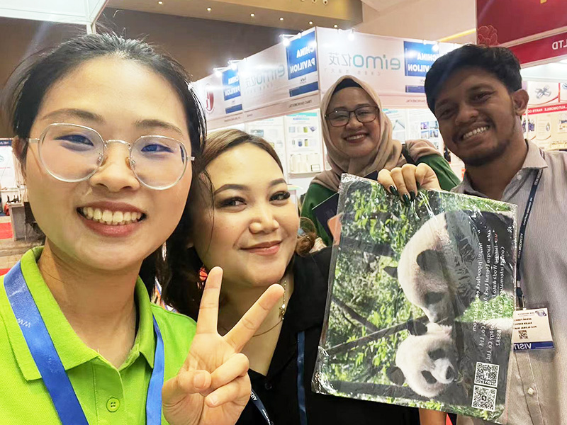 Woda sales team and customer at an automotive exhibition, with the customer holding a panda gift during a business meeting
