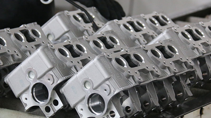 Mechanic cleaning newly manufactured cylinder heads in an automotive factory.