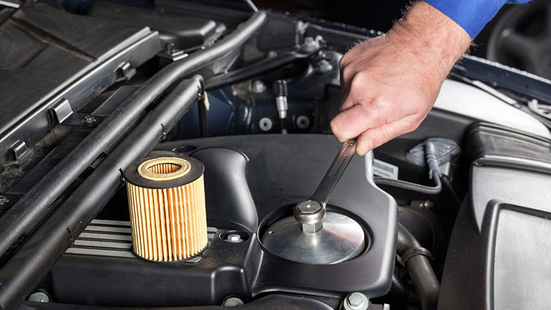 Auto mechanic performing an oil filter change on a modern car engine.