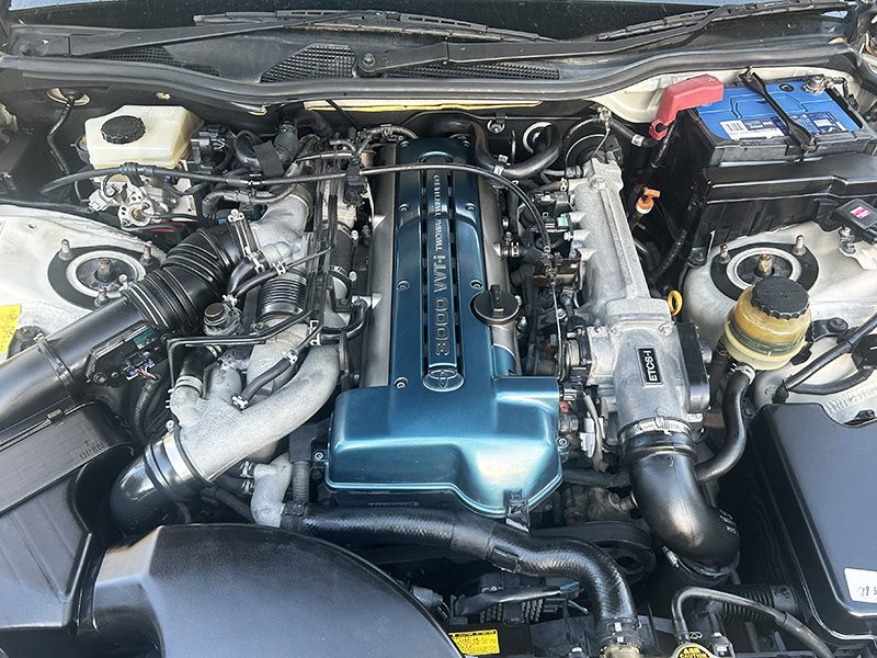 Close-up view of a Toyota Aristo engine bay showcasing the 2JZ-GTE inline-six engine with twin turbo setup.