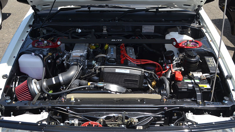 Toyota AE86 Corolla Levin 1600GT with hood open showing the engine bay and internal engine components.