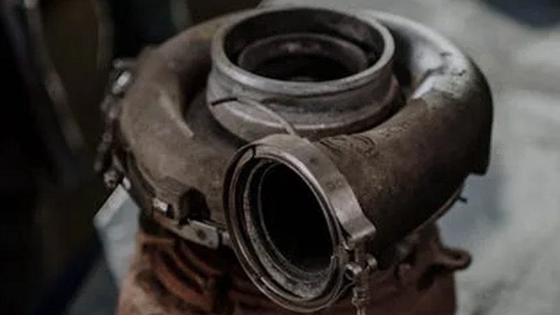 Close-up de um turbocompressor antigo mostrando sinais de desgaste e acúmulo de carbono.
