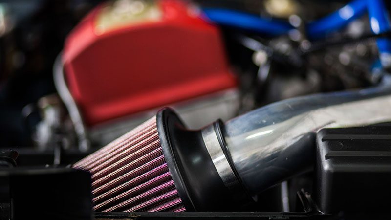 Close-up of a turbocharger air filter installed under the hood of a car, showing the filter housing and intake system components.
