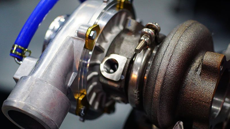 Close-up of a turbocharger unit installed on an engine, showing detailed housing and connections.