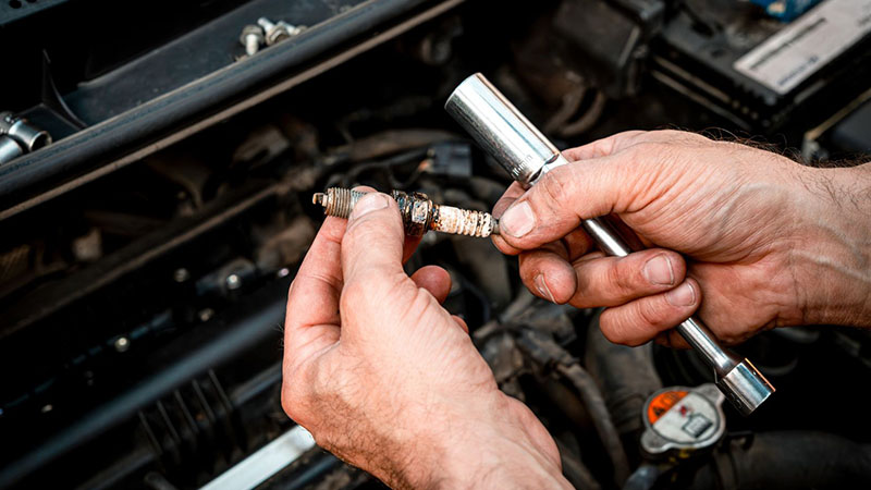 Mechanic checking a spark plug while diagnosing engine misfire issues.