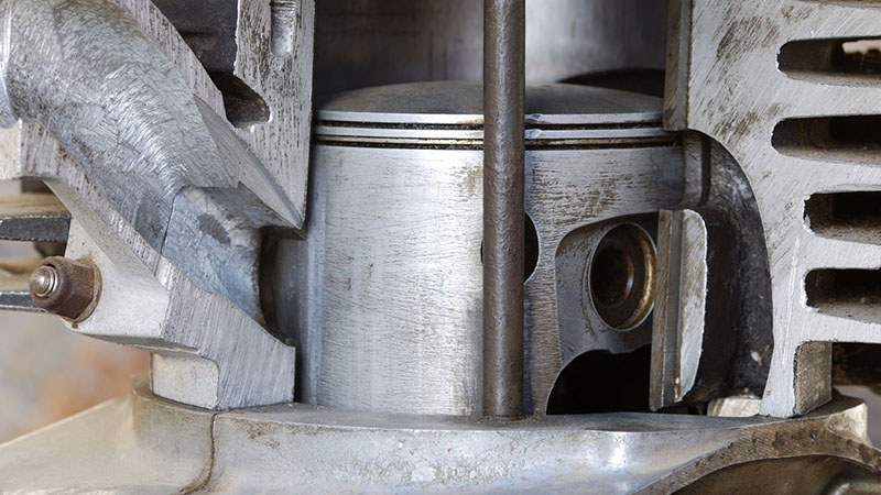 Open old four-stroke engine showing cylinders, pistons, and internal components.