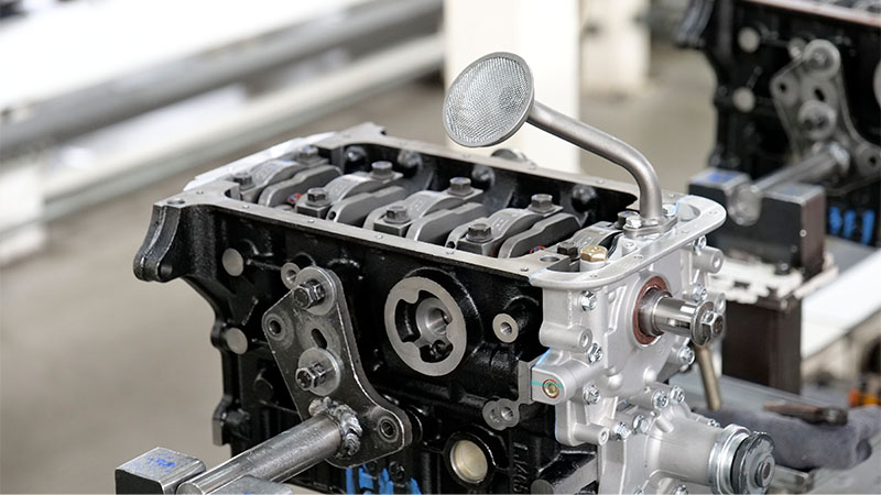 Engine block with assembled components during automotive engine production at a factory.