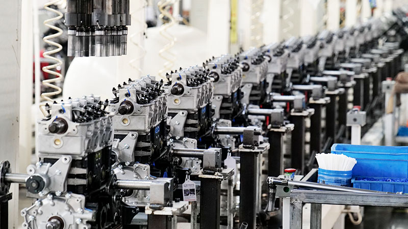 Wide view of an automotive engine assembly line with multiple engines lined up at a manufacturing factory.