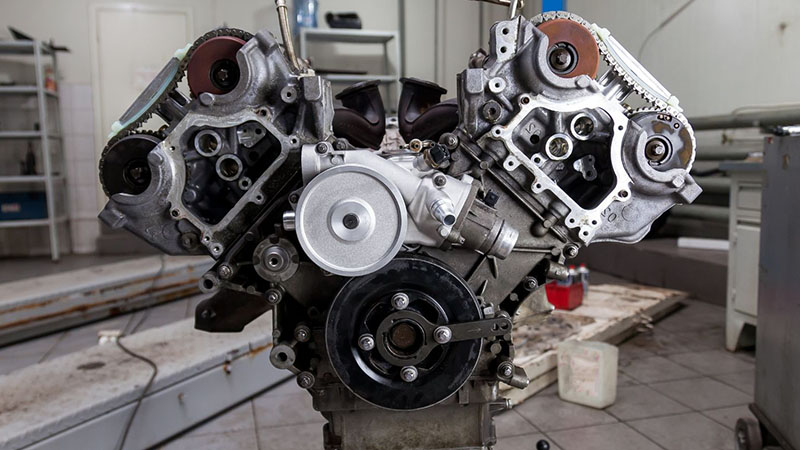 V8 engine mounted on a crane during factory handling, showcasing a wide range of automotive engine products.
